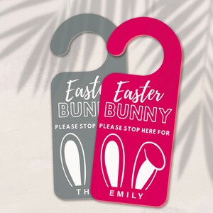 May include: Two door hangers with bunny ears and the text "Easter Bunny" in white. One is pink and says "Please stop here for Emily". The other is gray and says "Please stop here for [name]".