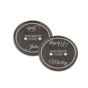 May include: Two black metal decision coins with the words "Decision Coin" and hearts on each side. One coin has the name "Julie" on it and the other has the name "Marley" on it.