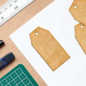 May include: Three blank brown paper tags with rounded corners and a hole punched in the top. The tags are on a white surface.