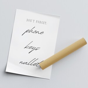 May include: A white poster with the text "DON'T FORGET: phone keys wallet" written in black cursive.