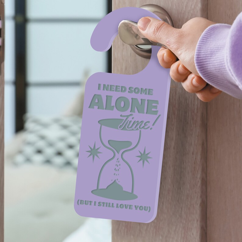 May include: Purple door hanger with the text "I need some alone time!" and an hourglass graphic. The text "(But I still love you)" is printed below the hourglass.