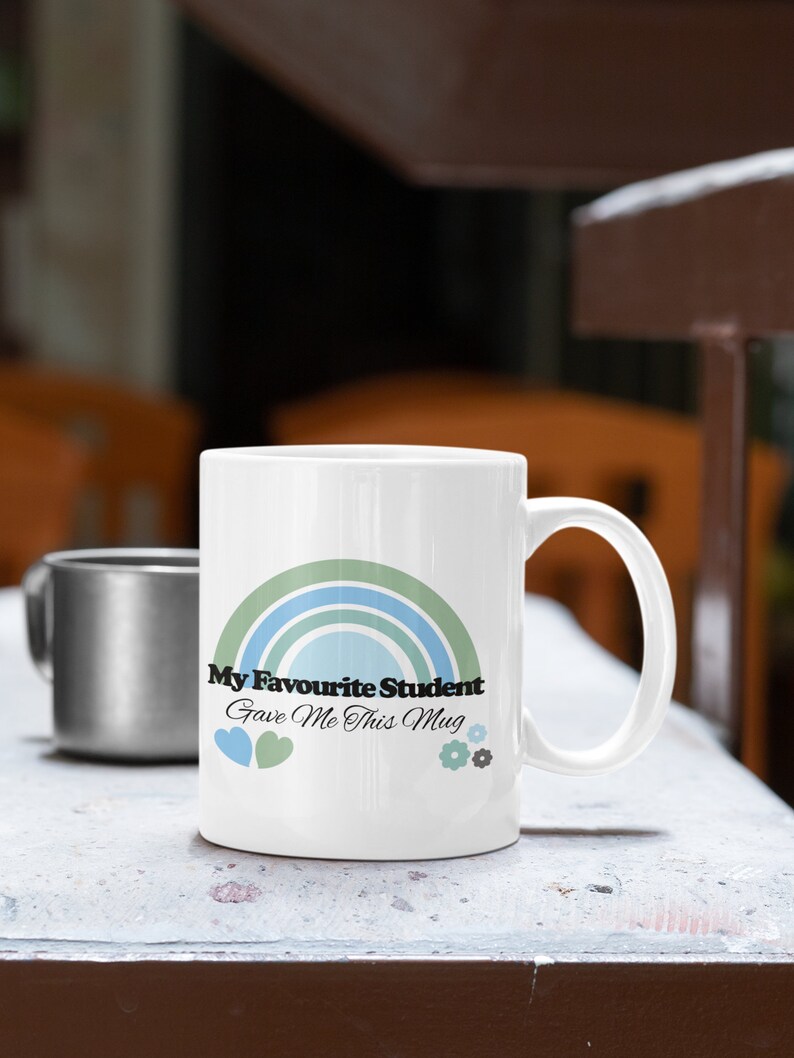 May include: White ceramic mug with a rainbow design and the text "My Favourite Student Gave Me This Mug".