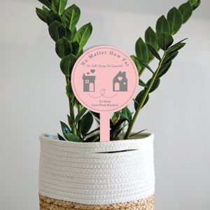 May include: Pink round plant stake with the text "No Matter How Far We Will Always Be Connected" with two houses and hearts. The text "To Mum Love From Rachel" is also included.