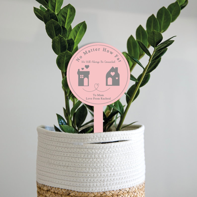 May include: Pink round plant stake with the text "No Matter How Far We Will Always Be Connected" with two houses and hearts. The text "To Mum Love From Rachel" is also included.
