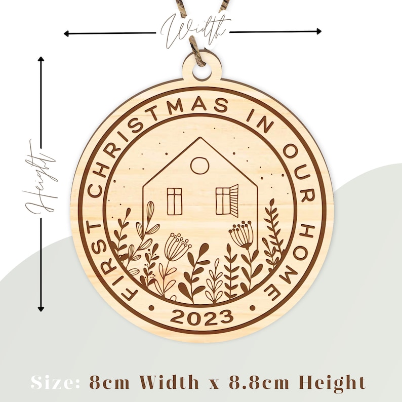 May include: A round wooden ornament with the text "First Christmas in Our Home 2023" and a house with a window and a moon in the center. The ornament is 8 cm wide and 8.8 cm high.