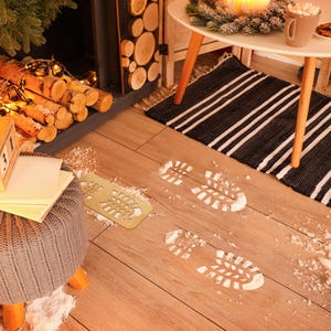 May include: A wooden floor with white footprints, a rug with black and white stripes, and a fireplace with a pile of logs in front of it.