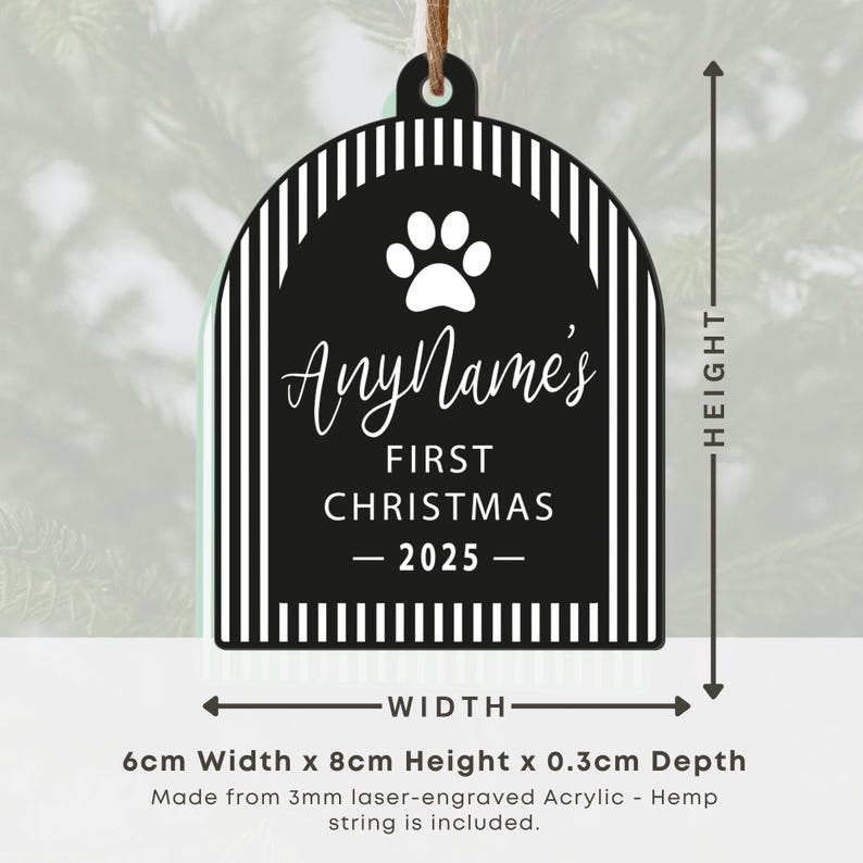May include: Black and white acrylic Christmas ornament with a paw print and the text "AnyName's FIRST CHRISTMAS - 2025-". The ornament is 6cm wide, 8cm high, and 0.3cm deep. Includes a hemp string for hanging.