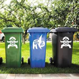 May include: Three green, blue, and black recycling bins with sloth stickers. The green bin has a sticker that says "Slow Down 20". The blue bin has a sticker that says "Slow Down". The black bin has a sticker that says "Slow Down 30".