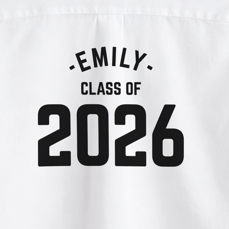 May include: White fabric with the text "-EMILY- CLASS OF 2026" in black. The text is centered and in a bold, sans-serif font. The fabric appears to be a shirt or other garment.