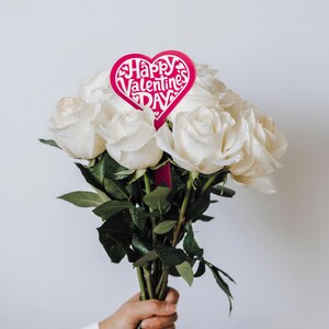 May include: A bouquet of white roses with a pink heart-shaped sign that says "Happy Valentine's Day".