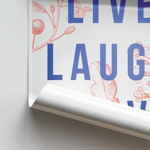 以下が含まれることがあります： 青い文字で「LIVE LAUGH LOVE」と書かれた白いポスターで、赤い花柄のデザインが施されています。