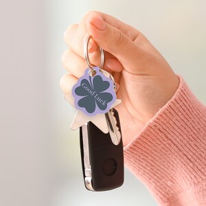 May include: A silver key chain with a purple four-leaf clover charm that says "Good Luck".