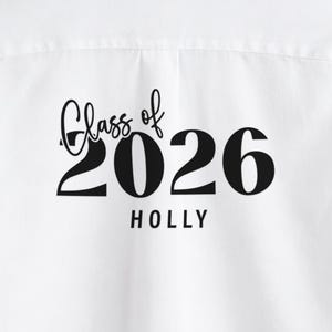 May include: White fabric with the words "Class of 2026 HOLLY" printed in black. The text is in a script font, with the year in a bold, sans-serif font.