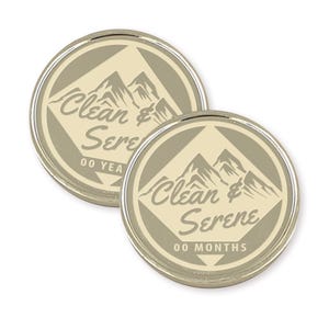 Puede incluir: Dos fichas redondas de color plateado con fondo beige. Las fichas presentan un gr&aacute;fico de una cordillera y el texto "Clean & Serene" con "00 YEARS" y "00 MONTHS" impreso debajo del texto.