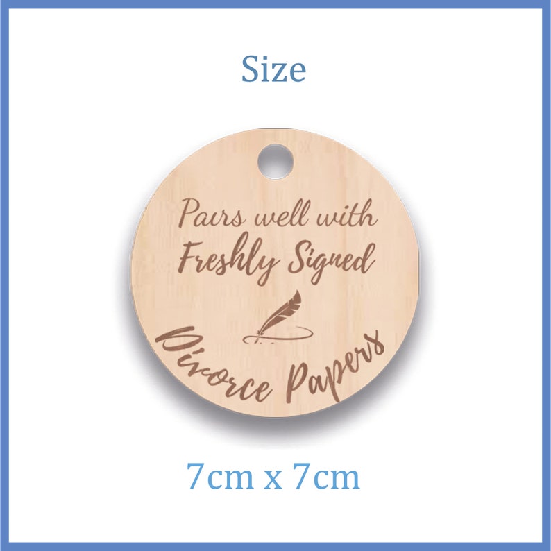 K&ouml;nnte beinhalten: Rundes Holzschild mit einem Loch oben. Das Schild hat einen Durchmesser von 7 cm und lautet "Pairs well with Freshly Signed Divorce Papers" mit einer Feder- und Tintenfassgrafik.