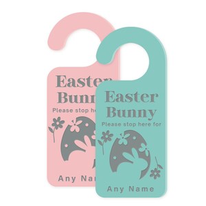 May include: Two Easter bunny door hangers, one pink and one teal, with a gray bunny silhouette inside an egg. The text on the hangers reads "Easter Bunny" and "Please stop here for... Any Name".