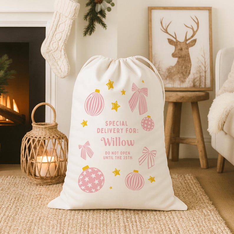 Puede incluir: Una bolsa de regalo navide&ntilde;a de color crema con cierre de cord&oacute;n. La bolsa est&aacute; decorada con adornos, lazos y estrellas rosas. El texto en la bolsa dice "SPECIAL DELIVERY FOR: Willow DO NOT OPEN UNTIL THE 25TH".