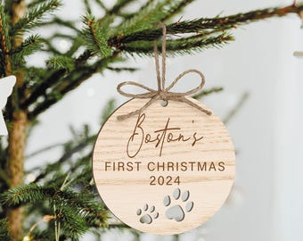 May include: A round wooden Christmas ornament with the text "Boston's First Christmas 2024" and two paw prints.