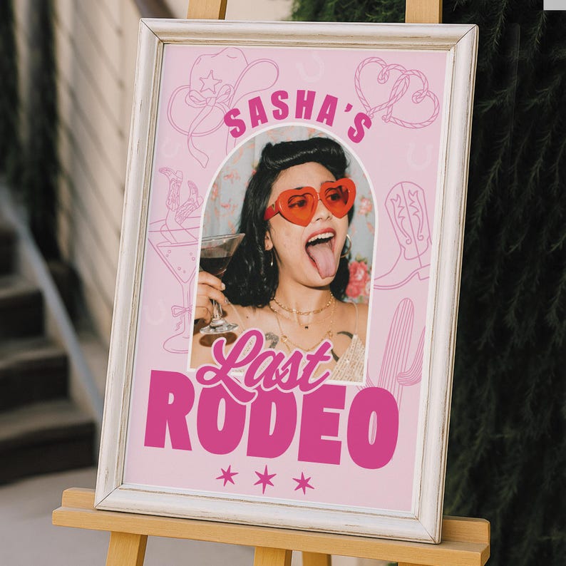 May include: A framed pink sign with the text "Sasha's Last Rodeo" in bold pink letters. The sign features a photo of a person wearing heart-shaped sunglasses and holding a drink. Cowboy-themed illustrations and stars complete the design.