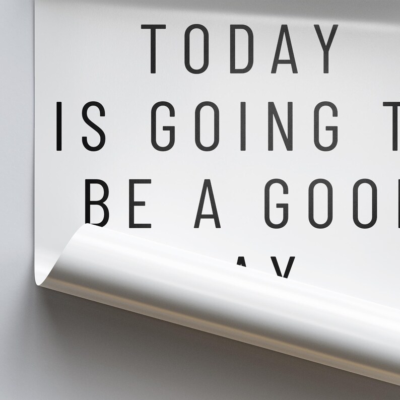 K&ouml;nnte beinhalten: Wei&szlig;es Poster mit schwarzem Text: &bdquo;TODAY IS GOING TO BE A GOOD DAY&ldquo;. Die untere rechte Ecke ist eingerollt und zeigt eine wei&szlig;e Oberfl&auml;che. Grauer Hintergrund.