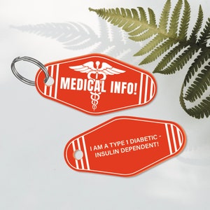 Puede incluir: Dos llaveros rojos con texto blanco y un s&iacute;mbolo m&eacute;dico. El llavero superior dice "MEDICAL INFO!" y el llavero inferior dice "I AM A TYPE 1 DIABETIC - INSULIN DEPENDENT!"