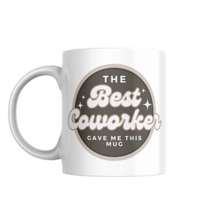 以下が含まれることがあります： 「The Best Coworker Gave Me This Mug」と書かれた茶色の円形デザインが施された白いセラミックマグカップです。