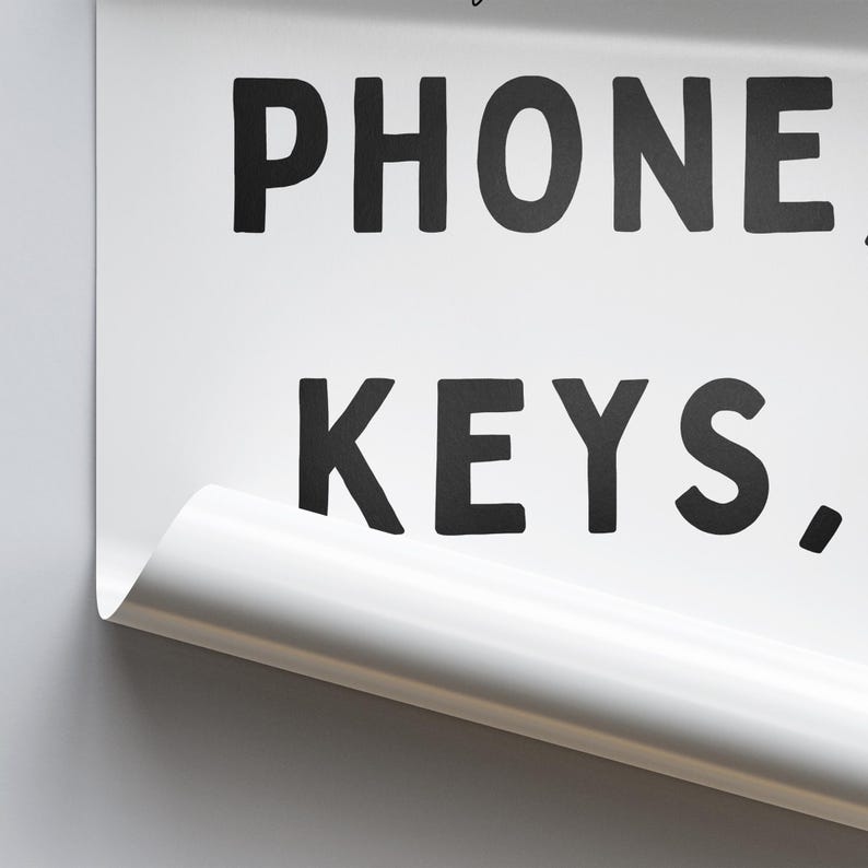 May include: White sign with black text that reads "PHONE, KEYS."