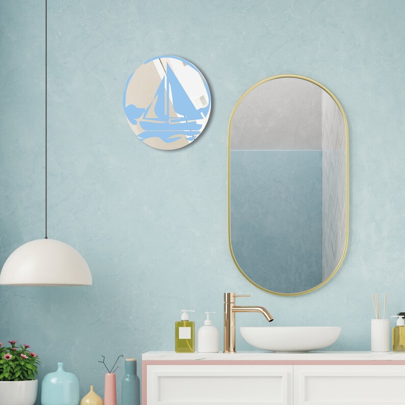 May include: A bathroom vanity with a white countertop and a gold oval mirror. The mirror is reflecting a blue wall with a round mirror featuring a blue sailboat design.