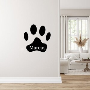 May include: Black paw print wall decal with the name "Marcus" written inside.
