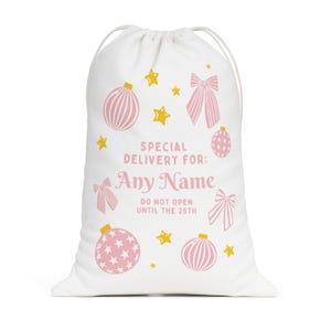 Puede incluir: Bolsa de regalo navide&ntilde;a blanca con cierre de cord&oacute;n. La bolsa est&aacute; decorada con adornos rosas, lazos y estrellas doradas. El texto en la bolsa dice "Special Delivery For: Any Name" y "Do Not Open Until the 25th."