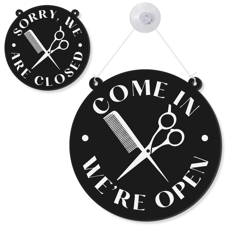 May include: Black and white round salon sign with the text "COME IN WE'RE OPEN" and "SORRY WE ARE CLOSED". The sign features a comb and scissors graphic. Includes a suction cup for hanging.