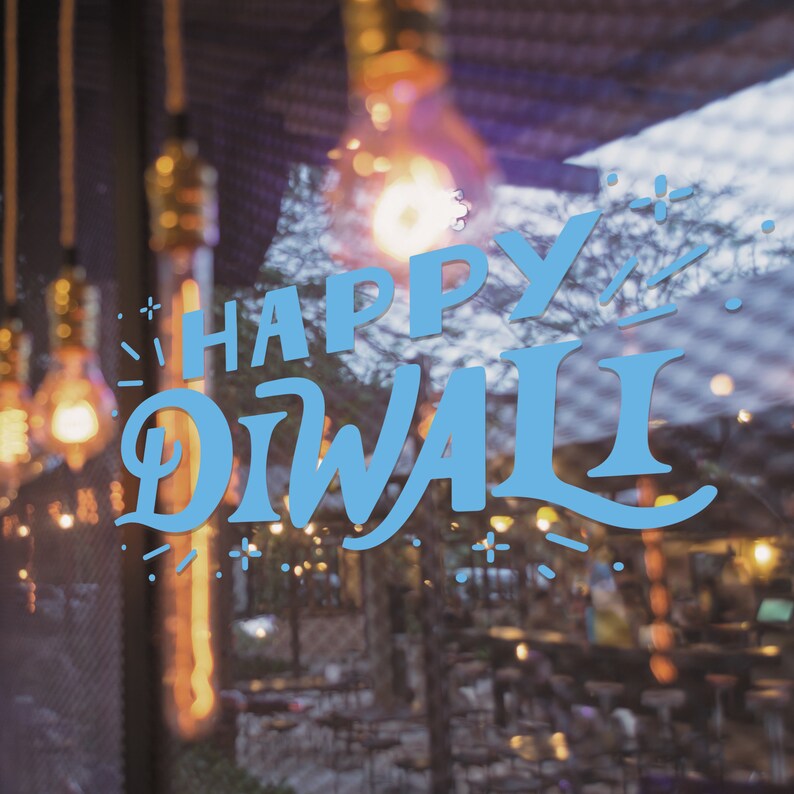 May include: A blurred image of a shop window with fairy lights and the words "Happy Diwali" written in blue on the glass.