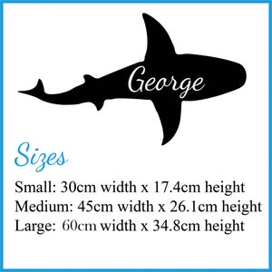 May include: Black silhouette of a shark with the name "George" written on it.  The image includes sizing information for small, medium, and large sizes in centimeters.