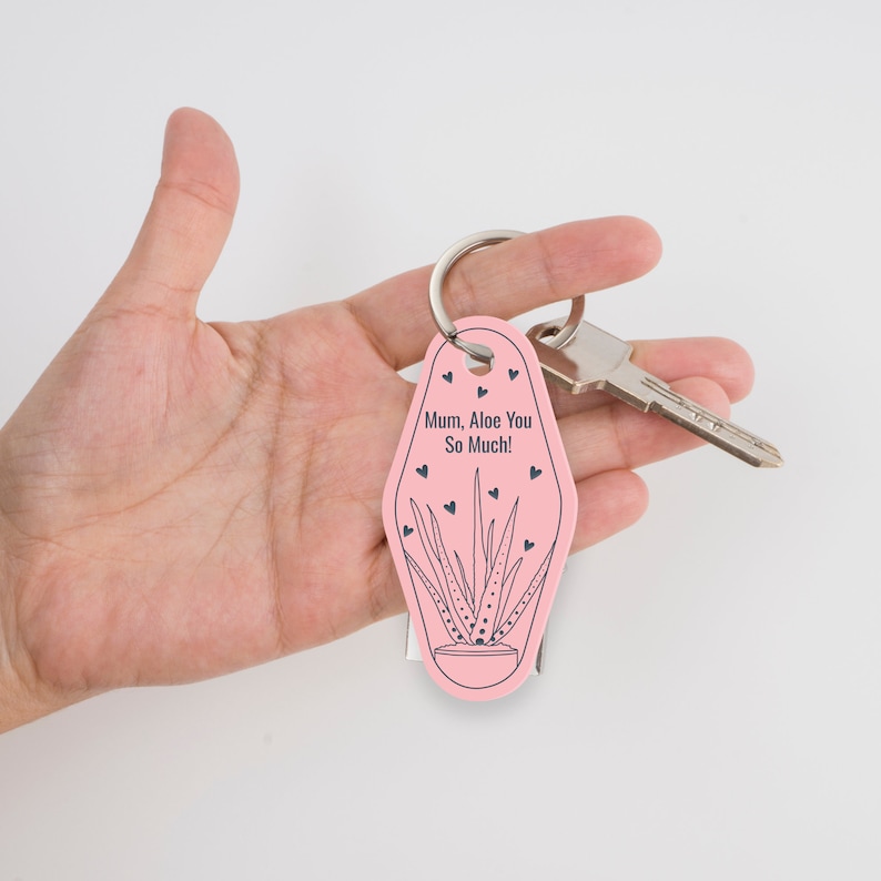 Może przedstawiać: R&oacute;żowy brelok do kluczy w kształcie motelu z czarno-białą ilustracją aloesu. Brelok ma napis "Mum, Aloe You So Much!" z małymi serduszkami wok&oacute;ł tekstu.