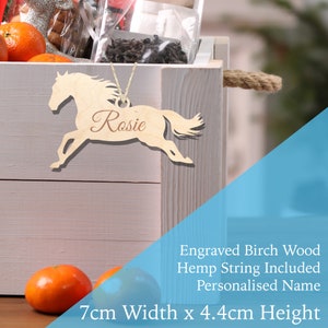 May include: Wooden horse ornament with the name "Rosie" engraved on it. The ornament is 7 cm wide and 4.4 cm high. It comes with a hemp string for hanging.