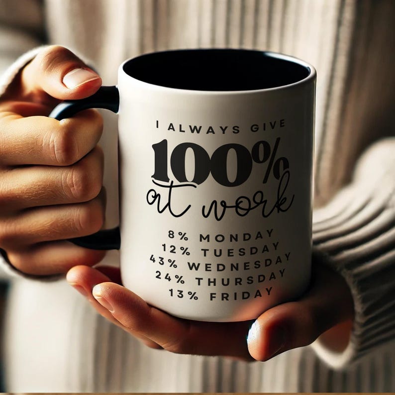 May include: White ceramic coffee mug with a black handle and black rim. The mug has black text that reads "I ALWAYS GIVE 100% at work" and a list of percentages for each day of the week: 8% Monday, 12% Tuesday, 43% Wednesday, 24% Thursday, 13% Friday.