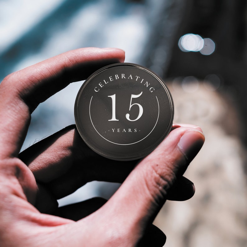May include: A black round button with the text "Celebrating 15 Years" in white.