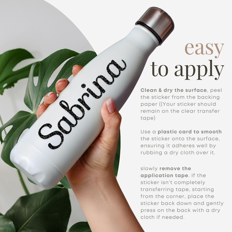 Op de afbeelding: Een witte waterfles met een zilveren dop en de naam "Sabrina" in zwarte glitterletters. De fles wordt voor een groene, bladerrijke achtergrond gehouden. De tekst aan de rechterkant luidt "easy to apply".