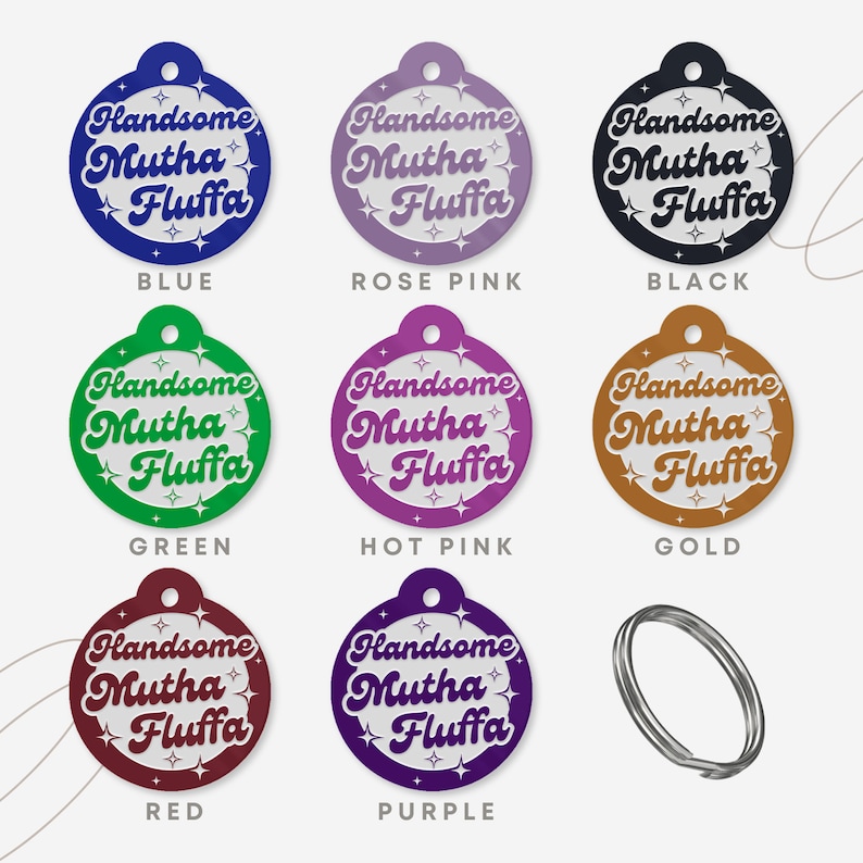 Op de afbeelding: Negen ronde huisdier-hangers in verschillende kleuren, elk met de tekst "Handsome Mutha Fluffa" in een wit retro-lettertype met witte sterren rond de tekst. De hangers zijn blauw, roze, zwart, groen, roze, goud, rood, paars en zilver.