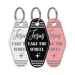 May include: Three keychains with the text "Jesus Take the Wheel" in black, white, and pink. Each keychain is shaped like a motel key tag with a silver ring.