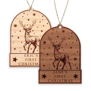 Op de afbeelding: Twee houten kerstversieringen met een hert-ontwerp en sneeuwvlokken. De versieringen zijn gepersonaliseerd met de tekst "Eric's First Christmas" en "Jane's First Christmas".