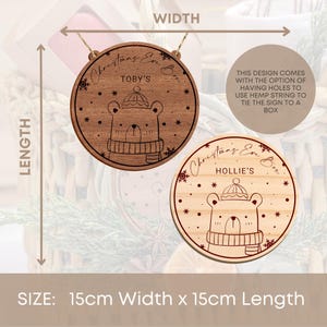 May include: Two round wooden Christmas Eve box signs with a bear illustration and snowflakes. The signs are 15 cm wide and 15 cm long. The text on the signs reads "Christmas Eve Box" and "Toby's" and "Christmas Eve Box" and "Hollie's".