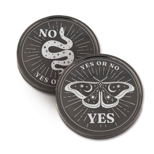 May include: Two black metal coins with a silver design. One coin features a snake with stars and the text "YES OR NO" and "NO". The other coin features a moth with stars and the text "YES OR NO" and "YES".