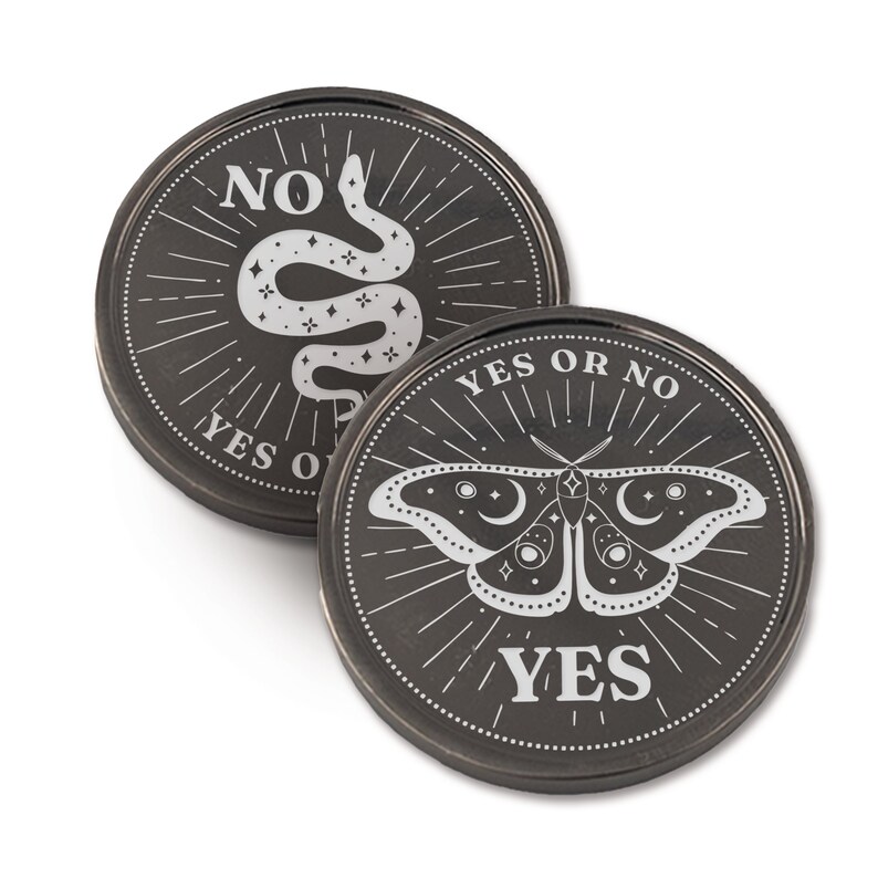 May include: Two black metal coins with a silver design. One coin features a snake with stars and the text "YES OR NO" and "NO". The other coin features a moth with stars and the text "YES OR NO" and "YES".