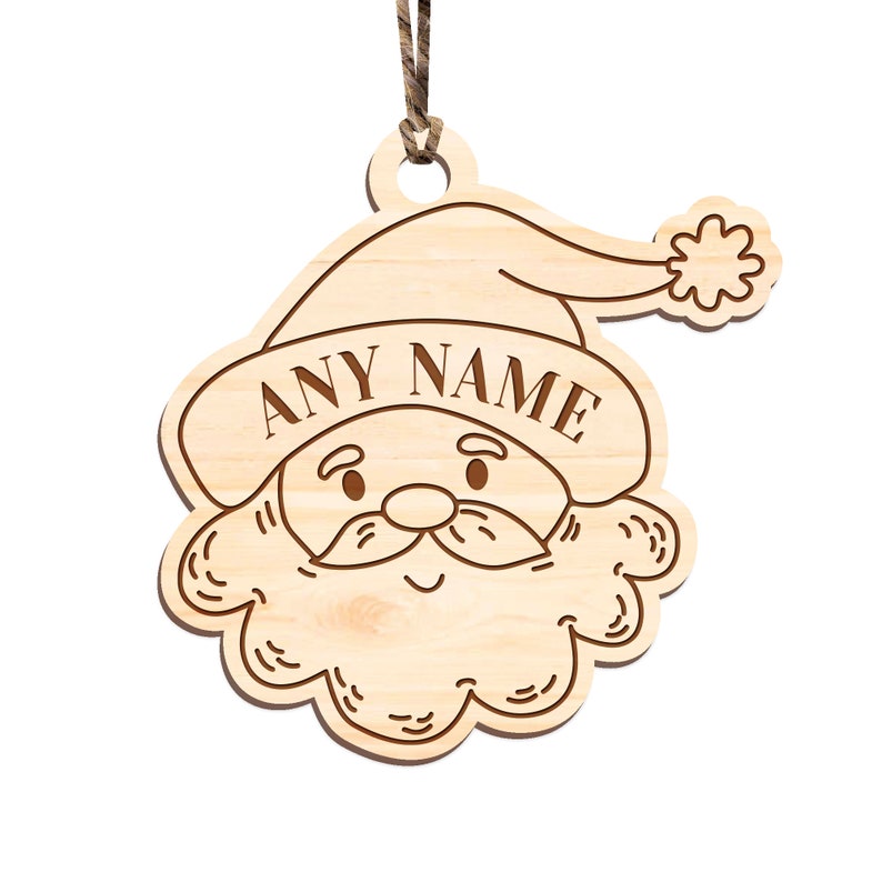 May include: A wooden Christmas ornament shaped like Santa Claus's face. The ornament has a brown string for hanging and the text "ANY NAME" is engraved on the hat.