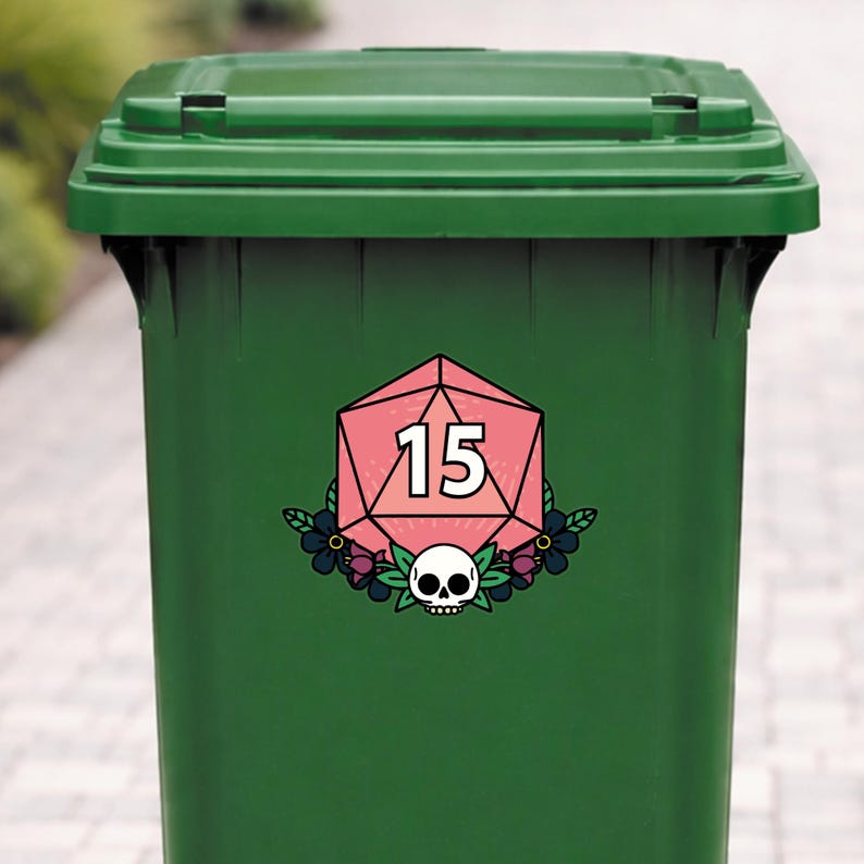 May include: A green trash can with a pink and white D20 die sticker. The sticker features the number 15, a skull, and floral accents. The trash can is made of plastic and has a hinged lid.