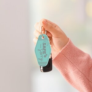 May include: A turquoise blue keychain with the text "Better Safe Than Sorry" in gray lettering. The keychain is in the shape of a motel key tag.