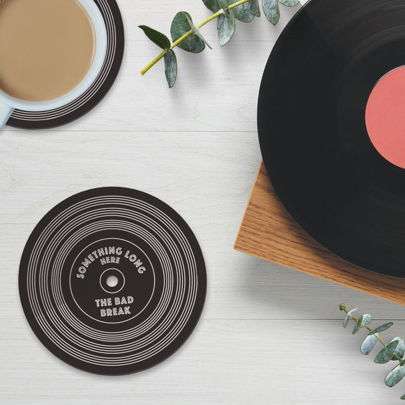 Puede incluir: Posavasos de vinilo negro y blanco con el texto "Something Here Long The Bad Break".