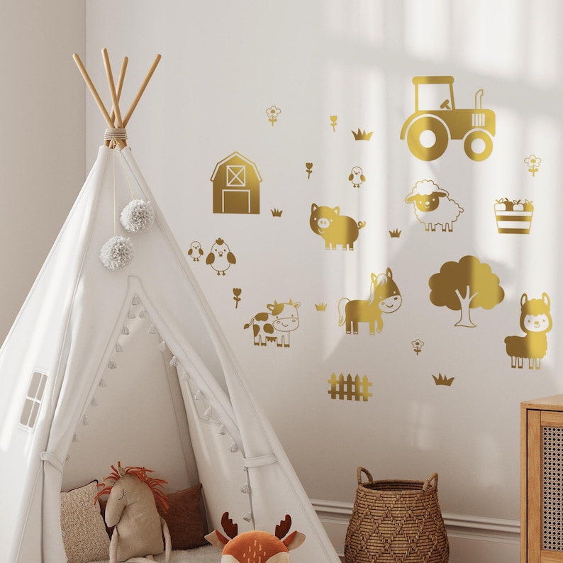 Op de afbeelding: Gouden wanddecoraties met boerderijdieren, waaronder een tractor, een schuur, een varken, een koe, een paard, een schaap, een lama en een boom. De stickers bevinden zich op een witte muur met een witte tipi-tent op de voorgrond.