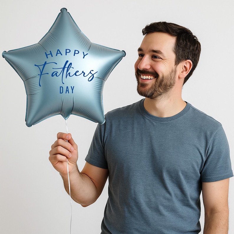 Puede incluir: Globo en forma de estrella azul claro con el texto "Happy Fathers Day" en letra cursiva. El globo lo sostiene una persona que lleva una camiseta azul. El fondo es blanco liso.